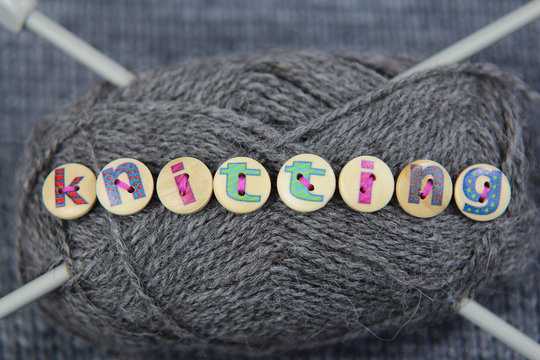 Grey ball of wall with the word knitting spelled in lettered but