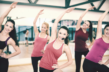group of smiling people stretching in the gym