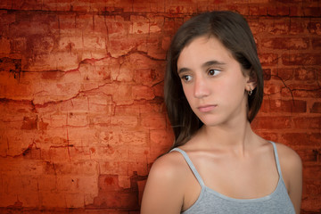 Sad teenage girl leaning on a bricks wall