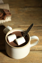 Hot chocolate with marshmallows in mug, on wooden background