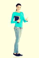 Fototapeta na wymiar Young student woman with book gesturing OK