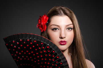 Beautiful young woman with flower and fan