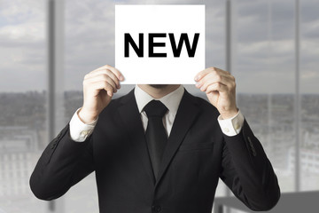 businessman hiding face behind sign new