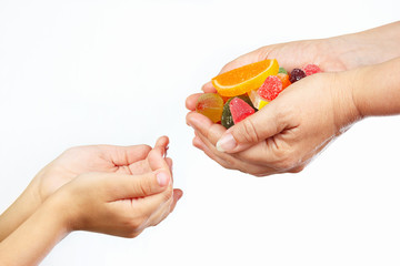 Hands of mother give colorful sweets and jelly in hands child