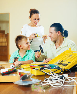 Happy Family Of Three Doing Something With  Tools