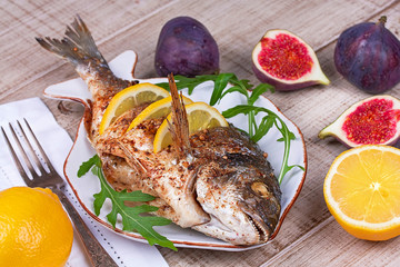 Whole grilled fish dorado served with lemon and figs;