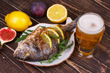 Whole grilled fish dorado served with lemon and figs;