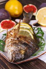 Whole grilled fish dorado served with lemon and figs;