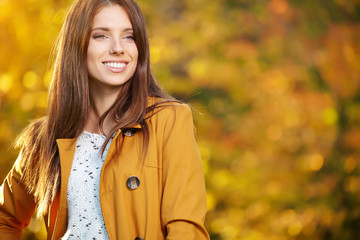 Beautiful elegant woman standing in a park in autumn