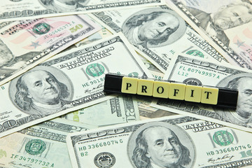 Word profit on pile of US dollar banknotes