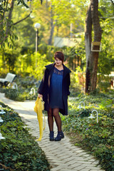 beautiful girl in a yellow coat and scarf in his hand walking th