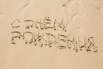 Happy Birthday message written on the sand in russian
