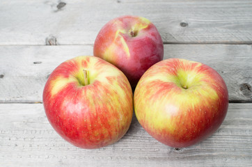 Three red apples on a wooden background