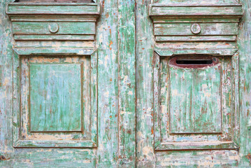 Old worn wooded door with green paint peeling off