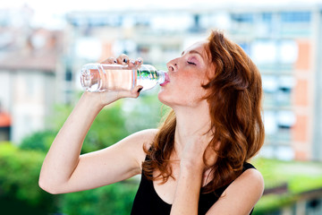 freckled woman drinks water from bottle