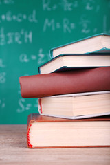 Books on wooden table on blackboard background