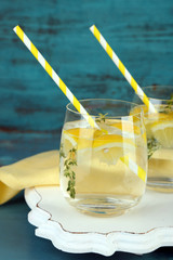 Tasty cool beverage with lemon and thyme, on wooden background