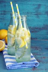 Tasty cool beverage with lemon and thyme, on wooden background