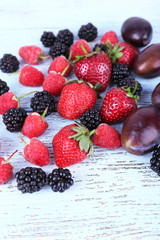 Different berries and plums on wooden table close-up