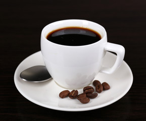 Cup of coffee and coffee beans on dark background