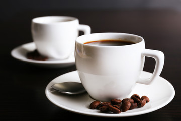 Two cups of coffee and coffee beans on dark background