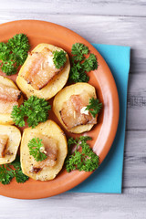 Baked potato with bacon on plate, on wooden background