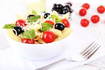 Pasta with tomatoes, olives and basil leaves in bowl