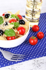 Pasta with tomatoes, olives and basil leaves in bowl