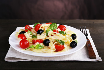 Spaghetti with tomatoes, olives and basil leaves