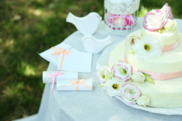 Beautiful wedding cake with flowers on table, outdoors