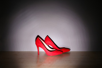 Pair of woman's red shoes on floor on light wall background