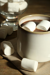Hot chocolate with marshmallows in mug, on wooden background