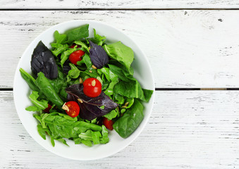 Fresh green salad in bowl on wooden table