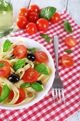 Spaghetti with tomatoes, olives and basil leaves