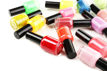 Fototapeta premium Colorful nail polish bottles scattered on white background, beauty and cosmetics industry, manicure and pedicure products