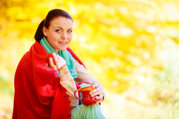 Girl relaxing in the autumn park enjoying hot drink