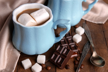 Cup of coffee with marshmallow and chocolate on wooden table