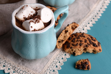 Cups of coffee with marshmallow and cookies on wooden table
