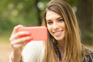 Young woman taking a selfie outdoors in autumn. No retouch