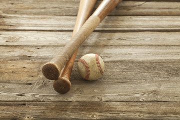 Old baseball and bats on rough wood surface