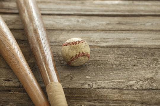 Old baseball and bats on rough wood surface