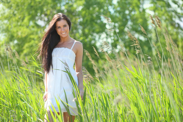 sexy young woman in a white dress in the grass