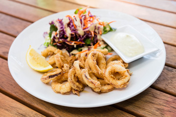 Deep fried calamari or squid with sauce on wooden table