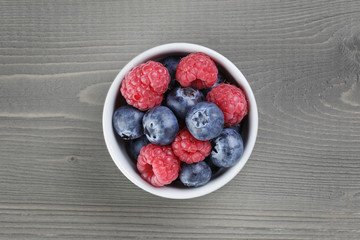 raspberries and blueberries in white bowl