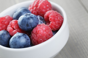 raspberries and blueberries in white bowl