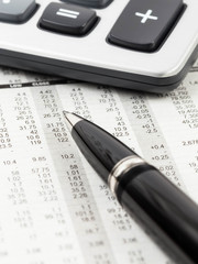 Pen, and calculator rest on stock price detail financial newspap
