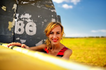 Fashion beautyful woman in dress stays near the old plane