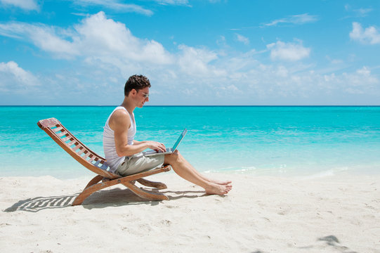 Man in chair with laptop on the beach