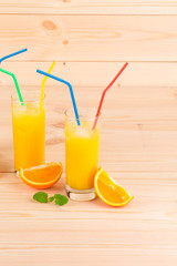 Orange juice and slices on wooden background.