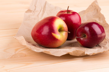 Fresh red apples on paper and wood.